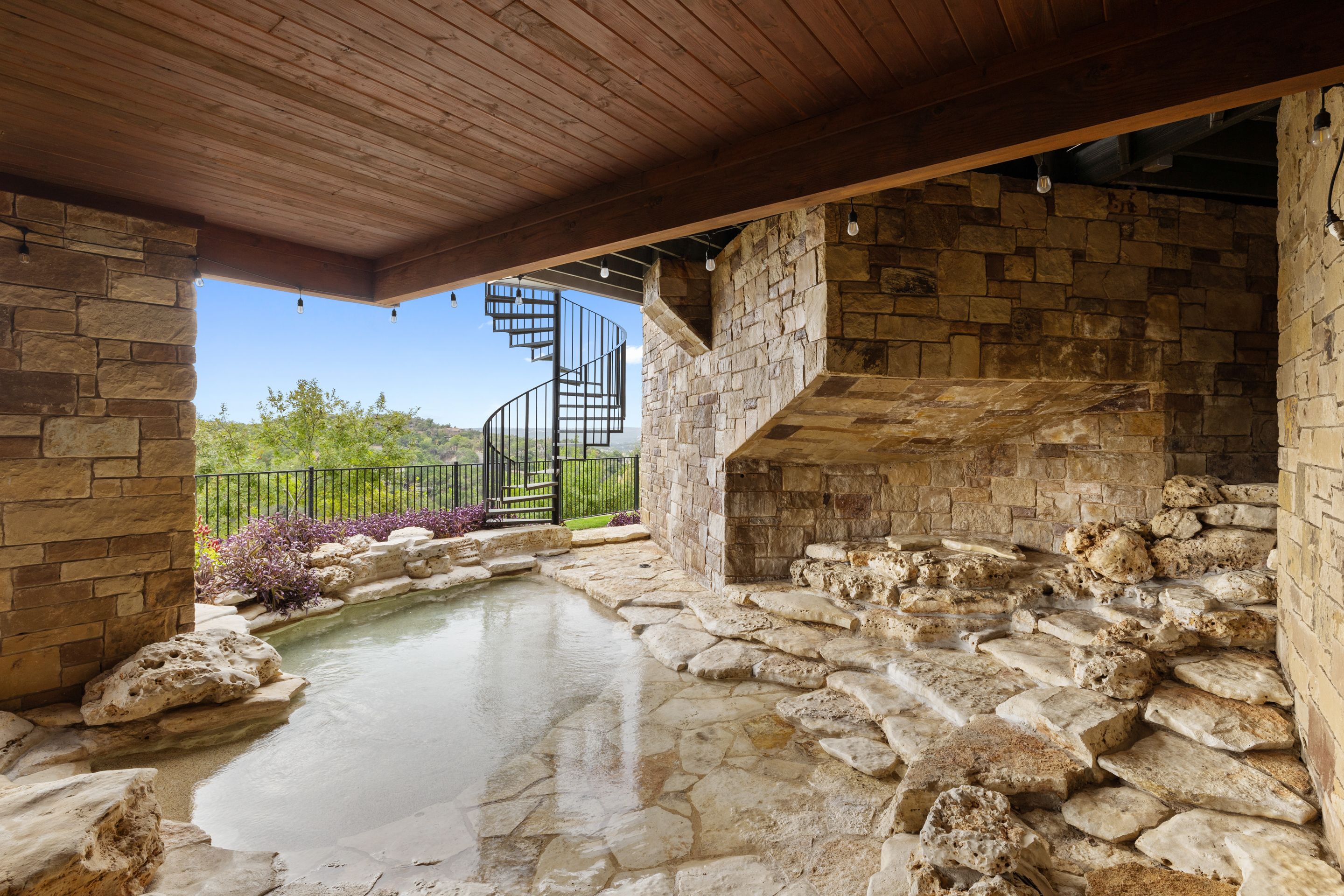 Renovated natural stone grotto and spillover feature with a Hill Country view