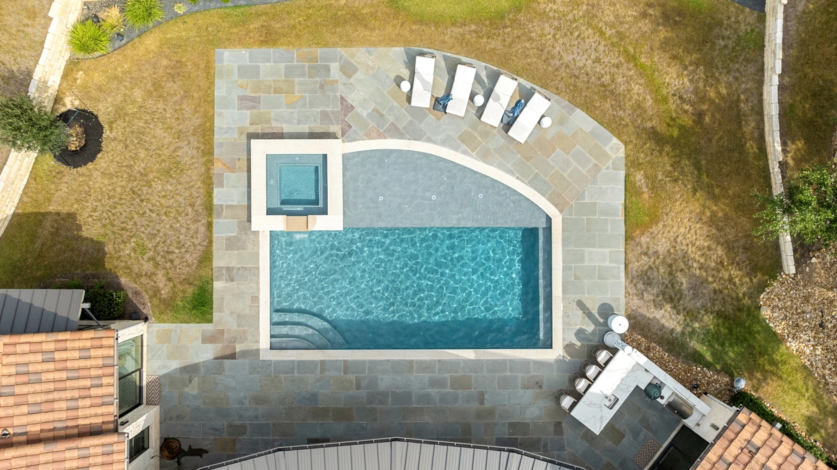 Aerial view of a resurfaced pool and spa with a new limestone patio